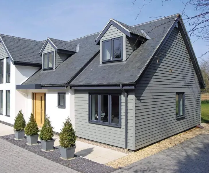 Modern house with a slate roof, dormer windows, and grey cladding, illustrating a successful loft conversion project.