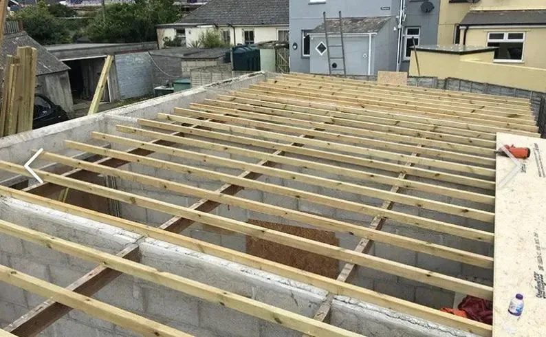 New timber roof joists being installed on a building extension or new build, with blockwork walls visible below.